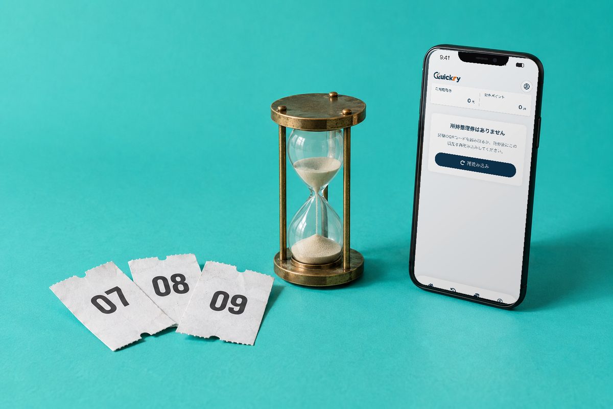 Quickry Pass の画面を表示したスマートフォンと砂時計・整理券